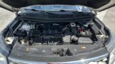 Open car hood revealing engine bay of a white SUV, showing battery and various hoses and components