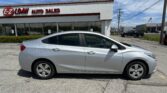 Silver sedan parked in front of EZ LOAN AUTO SALES building under blue sky with other cars in the lot