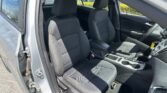 Inside view of a car's front seats from the open driver-side door, showcasing dark fabric seats and center console.