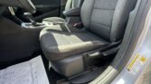 Interior of a car showing the front seats, center console with gear shifter, and papers on the floor/footwell area on the driver side, sunlight streaming in.