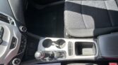 Interior of a car showing the front passenger seat, center console with gear shifter, cup holders, and control panel on the driver's side door area.
