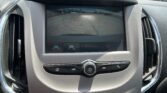 Back-up camera view on car display with orange parking guide lines over asphalt lot and distant parked cars in background, aiding parking.