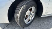 Close-up of a car wheel and tire in the wheel well of a silver vehicle, showing tread pattern and rust on the brake rotor.