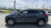 Dark SUV in foreground at a car dealership lot, with power lines and an EZ LOAN Auto Sales sign in the background.”