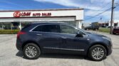 Blue SUV parked in front of EZ Loan Auto Sales storefront with red sign against a bright blue sky.