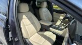 Interior of a dark blue SUV showing beige leather front seats and center console, opened driver's door visible on left.