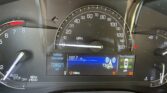 Close-up of a car dashboard with a large analog speedometer (0–160 mph) and a digital display below showing vehicle data, including odometer and radio info.