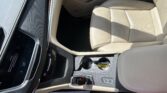 Beige leather car seat and center console viewed from above, with gear shifter and cupholders nearby