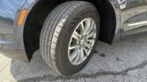 Close-up of a car's front wheel and tire inside the wheel well with orange side marker on the fender.