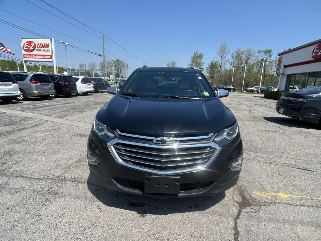 Front view of a black Chevrolet SUV parked in a car dealership lot with other vehicles and an E-Z Loan Auto Sales sign in the background