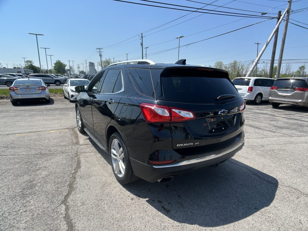 Black Chevrolet Equinox SUV parked in a busy lot, rear view with other cars and power lines overhead