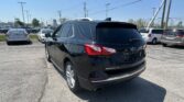 Black Chevrolet Equinox SUV parked in a busy lot, rear view with other cars and power lines overhead