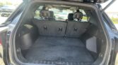 Open SUV rear hatch showing large cargo area with folded third-row seats and headrests visible behind.