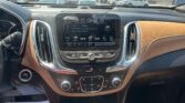 Infotainment screen in a car showing radio 96.9/97 Rock, with brown leather dash and dealership lot visible through the windshield behind it.