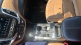 Tan leather car seats and center console seen from the driver's side, with controls and gear selector visible on the console area.
