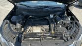 Open car hood showing engine bay with various hoses, battery, and fluid reservoirs visible