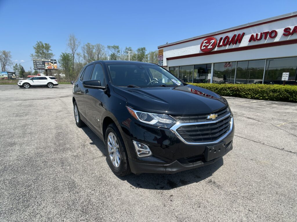 Close-up view of a black SUV in the dealership lot with an E-Z Loan Auto building in the background on a sunny day.