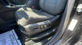 Car interior focusing on the driver’s seat and center console, with a gear shifter, seat controls, and a paper document on the floor mat nearby