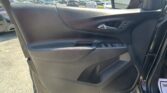 Car door interior with the armrest, chrome handle, and window controls; parking lot visible through the window and side mirror outside.