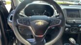 Steering wheel centered in the foreground with the dashboard gauges and a right-side touchscreen visible, in a sunny car interior.