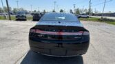 Rear view of a black Lincoln MKZ sedan in a car dealership parking lot with other cars and streetlights in the background.
