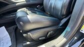 Black leather car interior focusing on the front seat and center console, with seat controls visible and sunlight on the upholstery.