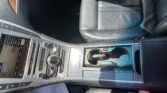Interior of a car showing black leather front seat and center console with a touchscreen and climate controls in view.