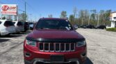 Front view of a red SUV in a car dealership lot with others and a large E-Z Loan sign in the background