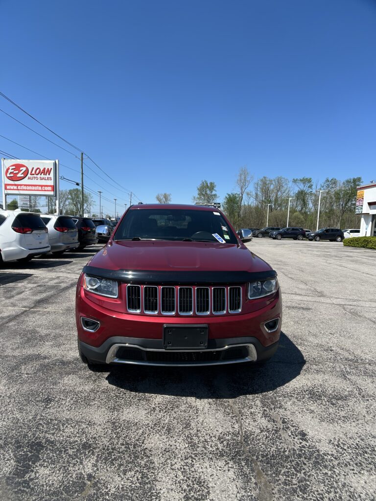 Front view of a red SUV in a car dealership lot with others and a large E-Z Loan sign in the background