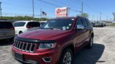 Red SUV in the foreground at an EZ LOAN Auto Sales lot, with other cars, a sign, and an American flag in a bright blue sky.