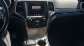 Interior of a car showing the center console with touchscreen, gear shifter, and cup holders while parked in a lot.