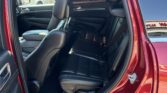 Open rear passenger door of a red SUV, showing black leather seats and headrests inside.