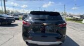 Rear view of a black Chevrolet Blazer SUV in a parking lot, with other cars and power lines under a bright blue sky.