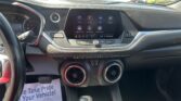Inside a car dashboard view showing a central touchscreen with app icons, steering wheel, push-start button, climate controls, and a paper floor mat that reads 'Take Pride Your Vehicle'