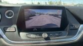Car infotainment screen showing the rearview camera with orange guidance lines in a dealership parking lot