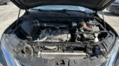 Blue car with its hood raised, exposing the engine bay and components like the air intake and battery in a parking lot.