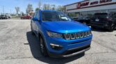 Blue Jeep SUV parked in a dealership lot with EZ Loan Auto Sales building in the background and other vehicles around.
