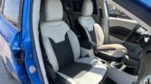 Open blue car door revealing the gray and black front seats, steering wheel, and center console inside the vehicle.