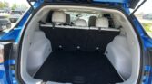 Open rear hatch of a blue SUV showing cargo area with folded-back third-row seats and beige interior?