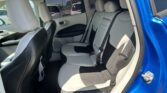 Interior of a blue SUV showing the back seat with light gray upholstery and black accents; three seat belts visible and headrests in place; window view of parked cars outside.