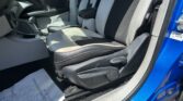 Inside a blue car's front cabin showing two-tone gray and black seats, center console, and partial steering wheel.