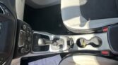 Front seat area of a car showing center console controls, gear shifter, and a two-tone beige and black interior.