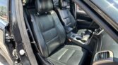 Interior of a black leather car showing the front seats, center console, and open driver door.
