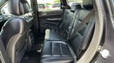 Rear row of a black-leather interior SUV with headrests and seat belts, viewed from the open rear door.