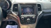 Car dashboard center console with touchscreen radio showing 106.5 Country and artist Rose, with surrounding air vents and climate controls.
