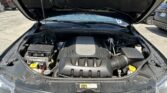Car hood open with the engine bay exposed, showing the battery, fuse box, and engine cover at the front of the vehicle.