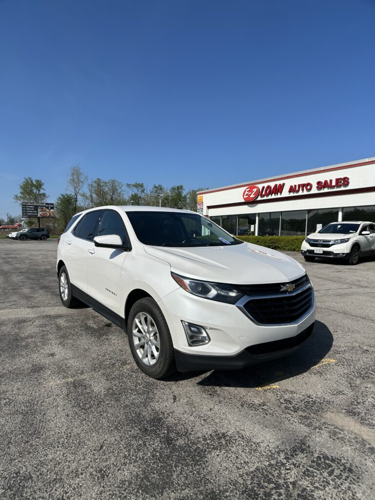 White Chevrolet Equinox parked in front of EZ LOAN Auto Sales on a sunny day.