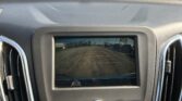 Car dashboard from the driver’s seat with the rear-view camera display showing parking-lot guidance lines behind the car
