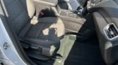 Right-hand-drive car interior with black fabric seats, center console, and gear shifter visible from the open driver's side door