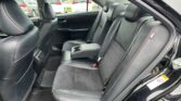 Back seat of a black car with leather upholstery and red contrast stitching, center armrest folded down.